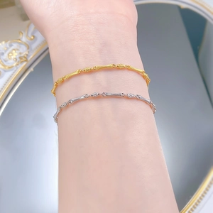 Close-up of gold and silver S925 sterling silver bamboo style bracelets on wrist