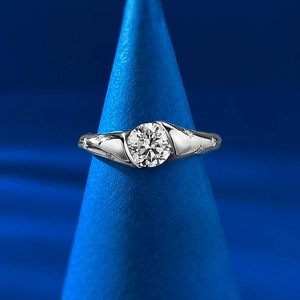 Détail d'une bague de fiançailles en diamant rond avec gravure d'étoiles sur support bleu