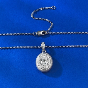 Oval silver pendant necklace with halo crystals and brushed metallic finish on blue background