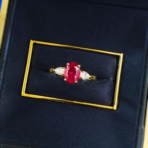 Eleganter Goldring mit ovalem Rubin und seitlichen Diamanten im Tropfenschliff im Etui