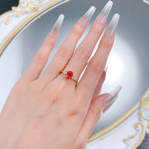 Detailansicht eines ovalen Rubinrings mit dreieckigen Diamanten an der Hand getragen