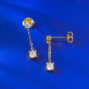 Dettaglio macro di orecchini a nappa in argento dorato con zirconi brillanti taglio tondo
