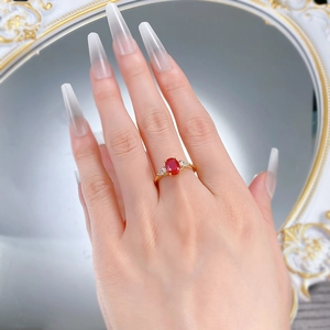 Detail eines ovalen rubinroten Rings mit Zirkonia-Verzierungen am goldenen Band