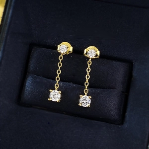 Dettaglio di orecchini pendenti in argento S925 dorato con diamanti rotondi lucidi