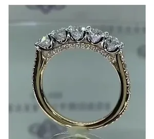 Détail d'une bague cinq pierres dorée avec pavage de diamants latéraux sur l'anneau
