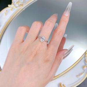 Close-up of oval-cut solitaire silver ring with pavé diamond band worn on finger