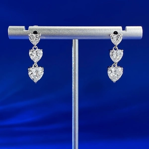 Macro shot of S925 silver triple heart drop earrings with sparkling cubic zirconia gems