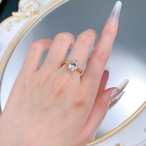 Close-up of 4-carat oval gemstone ring in gold finish on model hand with elegant background