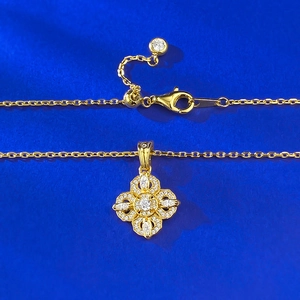 Détail d'un collier doré ajustable avec pendentif fleur à quatre pétales serti de zircons