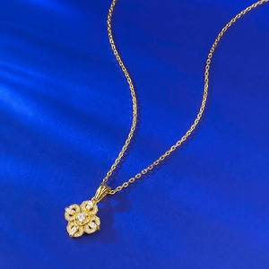 Gros plan du collier pendentif trèfle doré avec incrustations de zircons étincelants