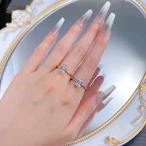 Close-up of emerald-cut crystal rings in gold and silver finish worn on a finger