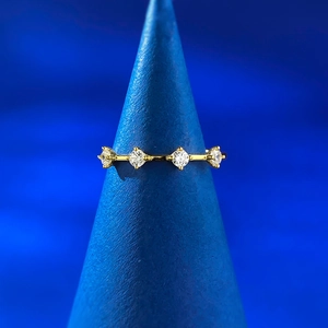 Macro shot of minimalist gold S925 ring featuring four round brilliant gemstones on a stand