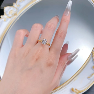 Close-up of S925 gilded ring with emerald cut clear gemstone shown in mirror reflection