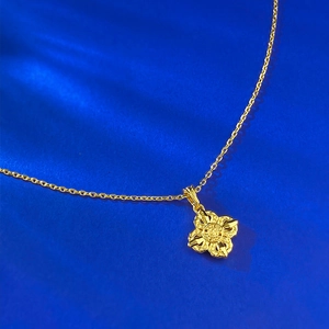Détail d'un pendentif croix Vajra doré sur une chaîne avec un fond bleu vif