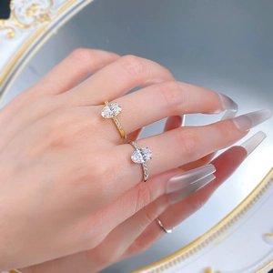 Detailed view of two oval-cut crystal rings in gold and silver plating with side accents