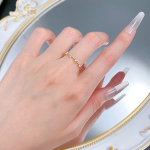 Close-up of minimalist gold ring with four round white zircons on a woman's finger