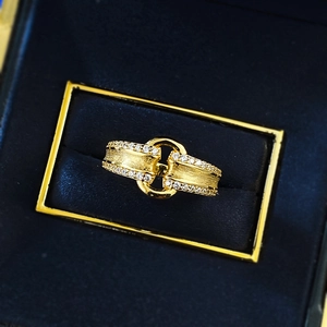 Macro detail of brushed gold ring with interlocking circles and sparkling zircon rows