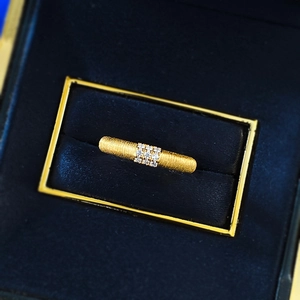 Macro shot of brushed gold ring with nine diamonds set in a high-end blue velvet jewelry box