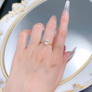 Detail of gold oval gemstone ring with side stones worn against a vintage mirror