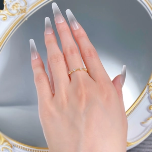Detail view of a wavy gold ring with four sparkling zircons worn on a finger