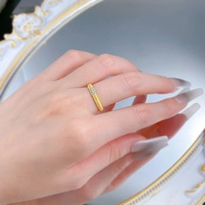 Macro detail of gold-finish brushed ring with four small diamonds worn by a model