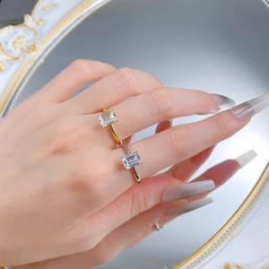 Dettaglio di anelli minimalisti in oro e argento con pietre quadrate indossati da modella