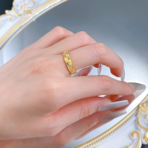 Close-up of a brushed gold woven ring with sparkling zircons worn on a finger