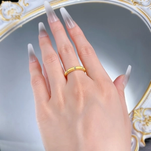 Detail of a matte gold 925 silver ring with zircons worn on finger against mirror