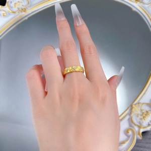 Detail of woven texture gold ring with small zircon stones worn on person