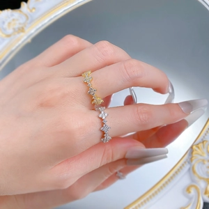 Close-up of four-leaf flower stacking rings with micro-pave zircons in gold and silver