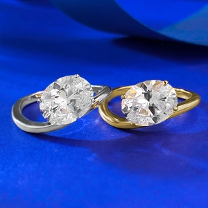 Detail of silver and gold S925 rings with oval-cut stones on S-shaped twisted bands