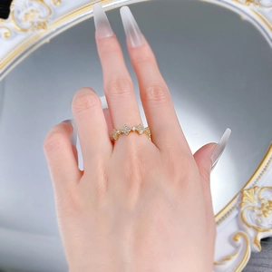 Close-up of a gold-plated flower ring with sparkling crystals on a model's hand