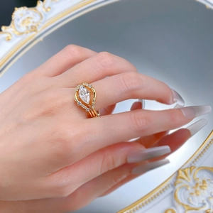 Close-up of golden marquise-cut diamond ring on finger with elegant mirror reflection