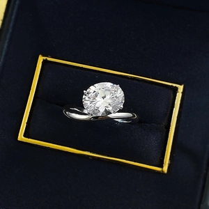 Close-up of sparkling 8x10mm oval-cut gem ring with bypass band in blue velvet gift box