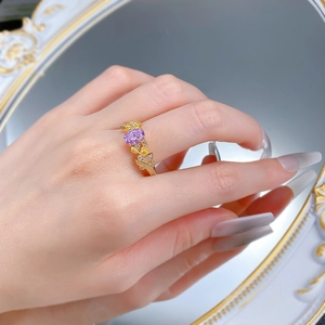 Détail d'une bague florale dorée avec gemme rose ovale et pétales jaunes ciselés