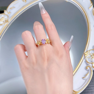 Détail d'une bague en argent S925 avec pierre violette et design floral doré au doigt