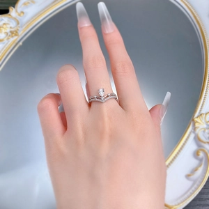Elegant silver crown ring with pear-cut stone on finger reflected in a mirror