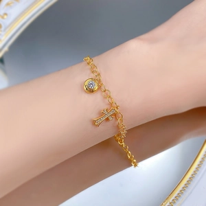 Dettaglio di un bracciale in argento S925 dorato con ciondolo a croce e zirconi al polso