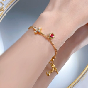 Gros plan d'un bracelet en argent S925 doré avec croix et cornaline sur un poignet femme