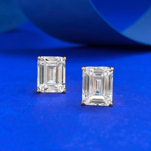 Boucles d'oreilles taille émeraude 7x9mm avec monture dorée sur un fond bleu chic