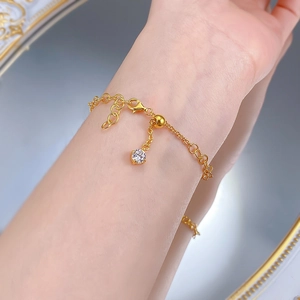 Dettaglio ravvicinato di un bracciale a croce dorato con chiusura a scorrimento regolabile