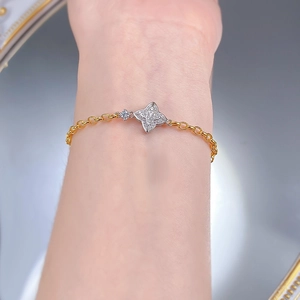 Close-up of a gold chain bracelet with a sparkling paved four-pointed star pendant