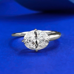 Macro detail of oval cut gemstone in four-prong silver setting on blue background