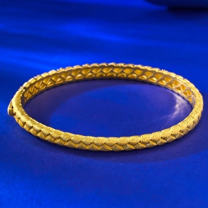 Close-up of golden woven texture and geometric hollow interior of the wheat braid bangle