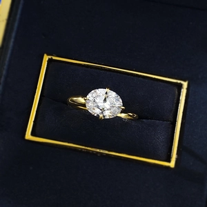 Macro shot of a 7x9 oval-cut solitaire ring with gold plating in a blue jewelry gift box