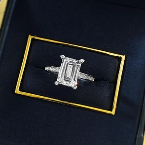 Elegant emerald cut silver ring with pave-set diamonds on a blue jewelry box