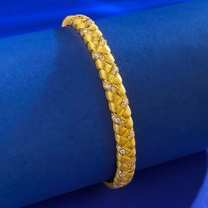 Detail of gold plated woven bangle with matte finish and micro pavé crystals