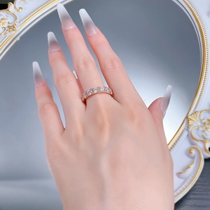 Close-up of rose gold eternity ring with 4mm round-cut diamonds on hand by mirror