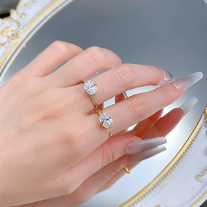 Detailed view of oval cut crystal rings in gold and silver finish worn on fingers