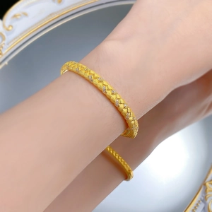 Macro detail of gold-plated woven texture bracelet with sparkling crystals on wrist
